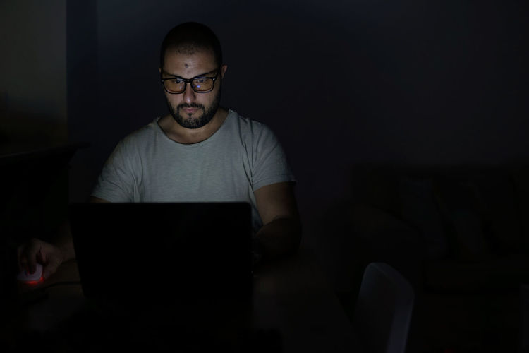 Man with eyeglasses working late at home with laptop computer