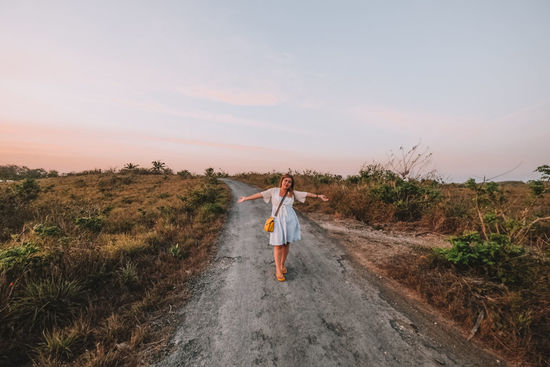 Full length of woman standing on road against sky during sunset