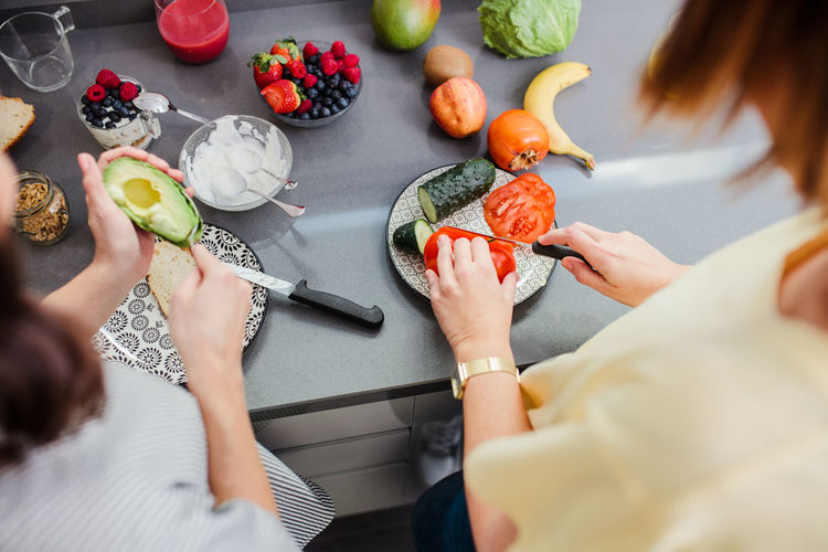 Women preparing healthy food with vegetables in kitchen having fun concept dieting nutrition.