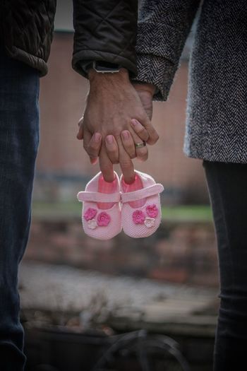 Midsection of couple holding baby booties 