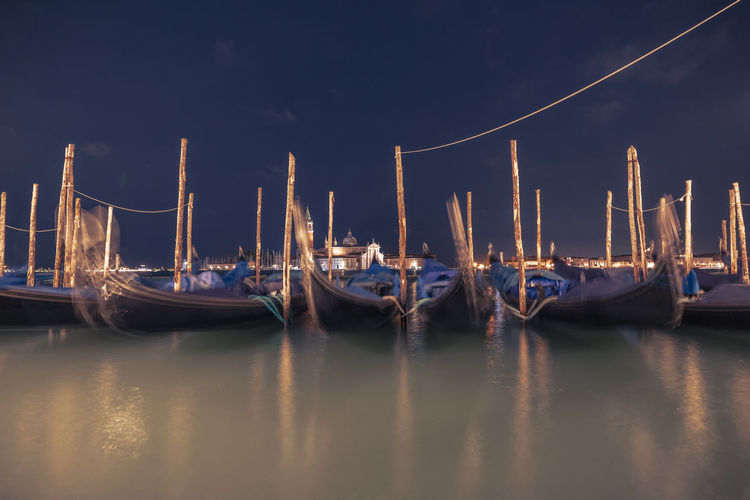 Boats moored in sea against sky at night
