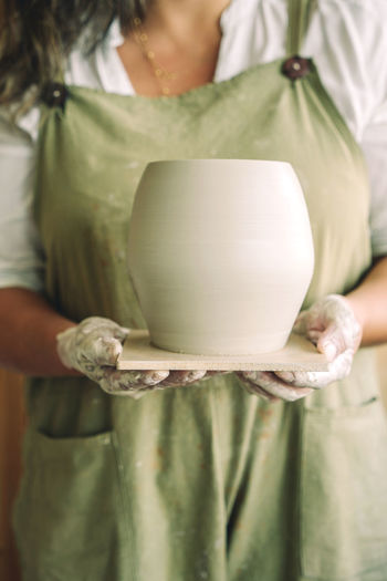 Midsection of woman holding jug in workshop