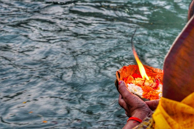Cropped image of woman with religious offerings praying in river