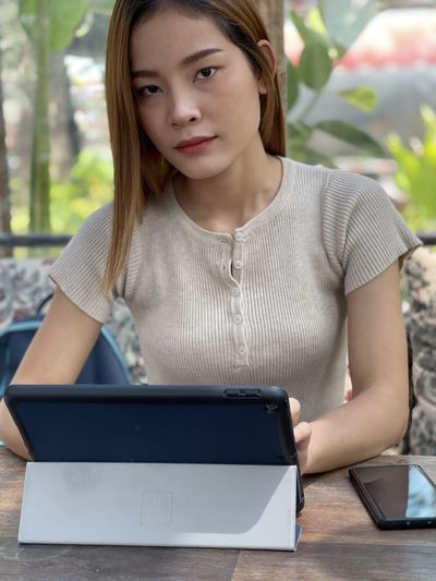 Portrait of young woman using phone on table
