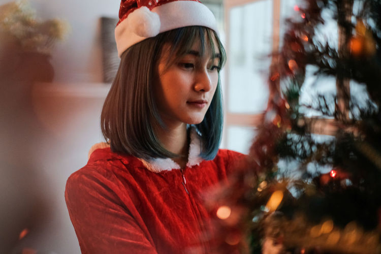 Portrait of young woman looking away at christmas tree