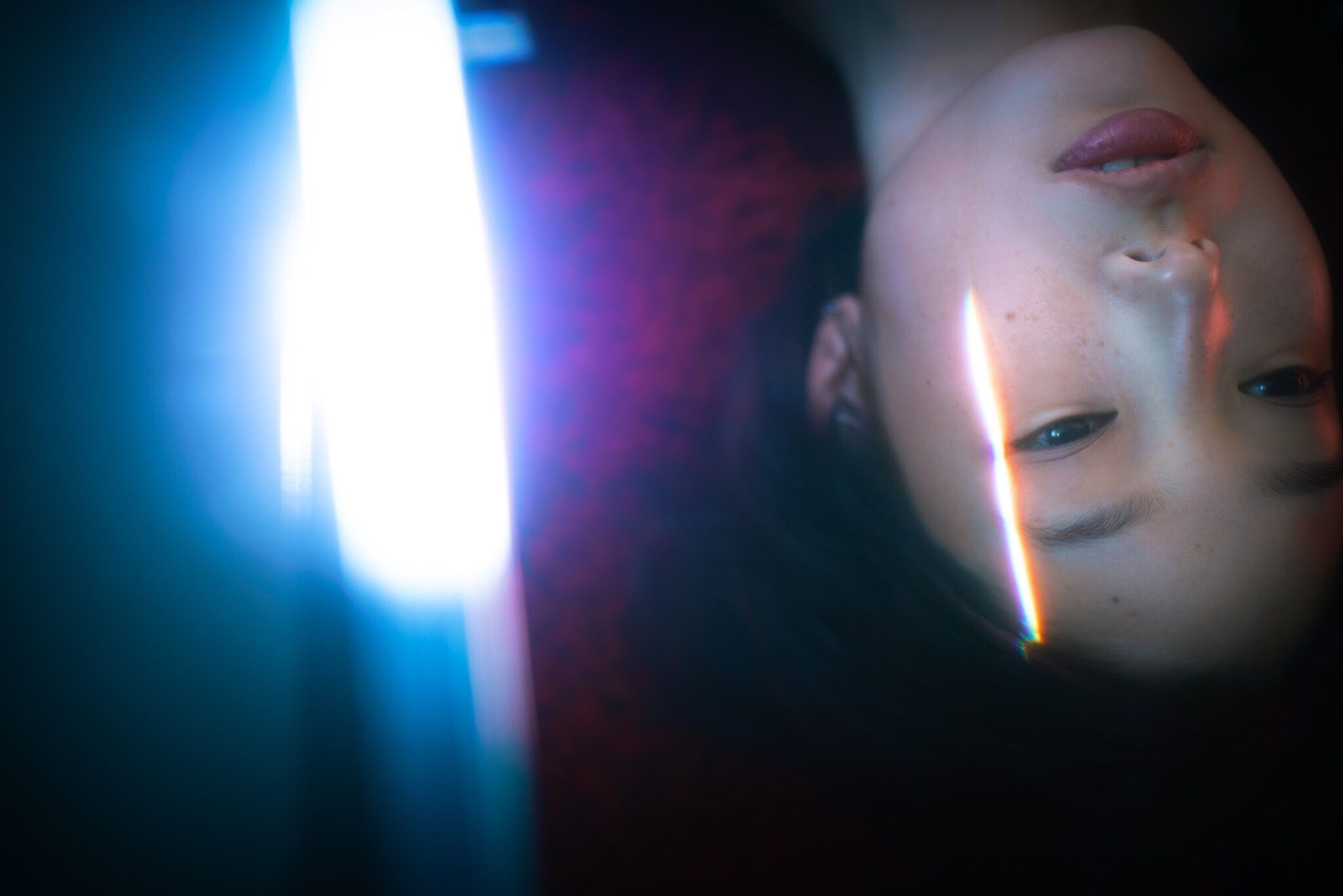 headshot, young adult, indoors, looking at camera, young women, person, human face, looking, lens flare, sun, contemplation, focus on foreground, bright, darkroom