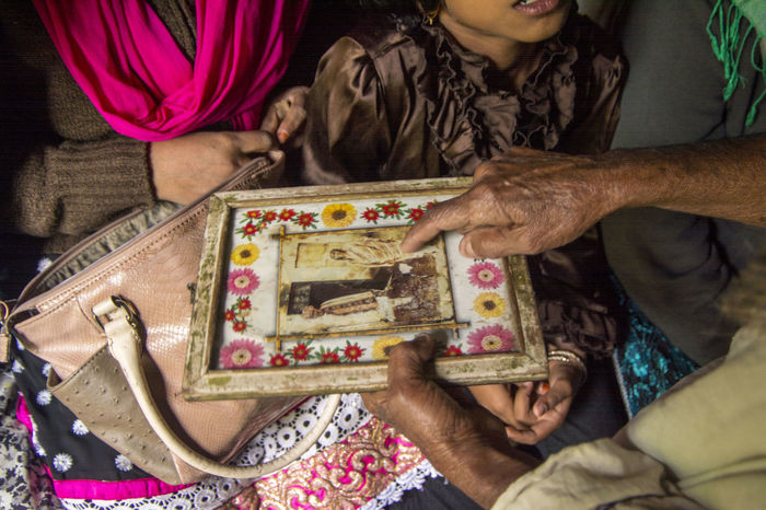 Cropped man showing old photograph to woman and her daughter