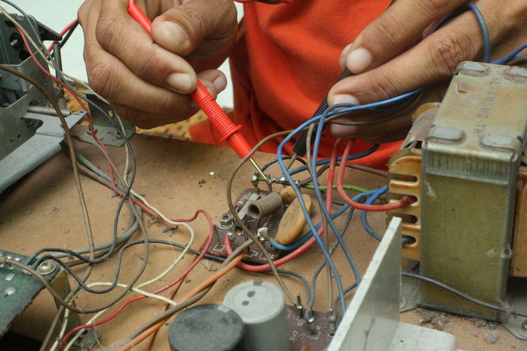 Cropped hands of male technician repairing radio