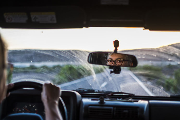 Reflection of senior woman seen in rear-view mirror