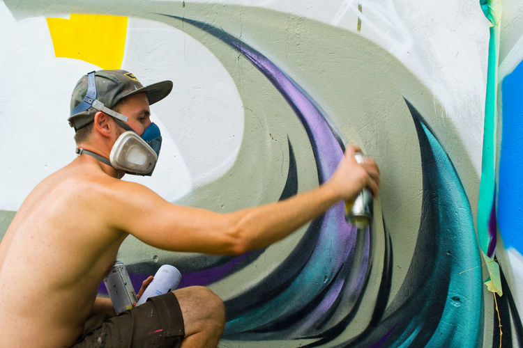 Close-up of a man spray painting wall