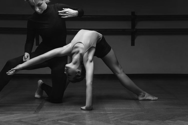 Portrait of a choreographer's teacher helping a little girl to pose correctlyin a dance studio