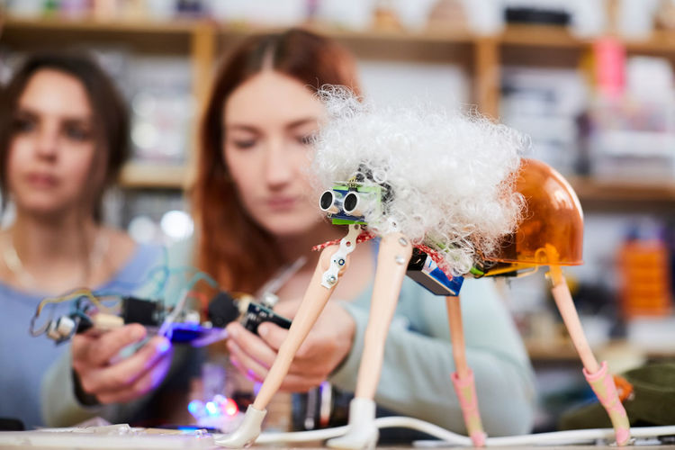 Young female inventors making robot model at workshop