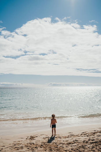 Boy walking into the water at the beach on a sunny day on vacation