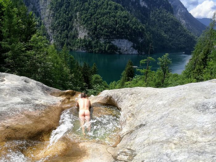High angle view of naked man in stream against mountain