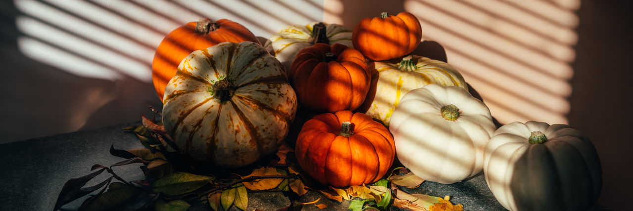 Happy thanksgiving text with background of pile of different pumpkins with strong shadows. 