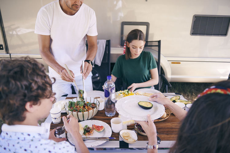High angle view of family having food against camper trailer