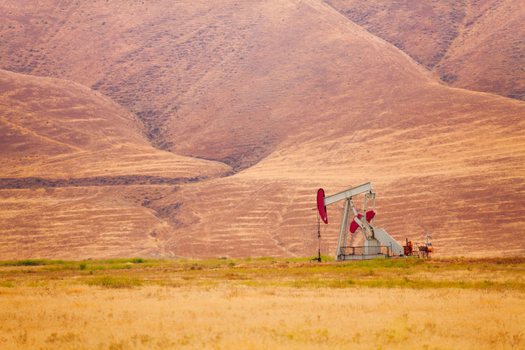 Drilling rig in desert against mountains
