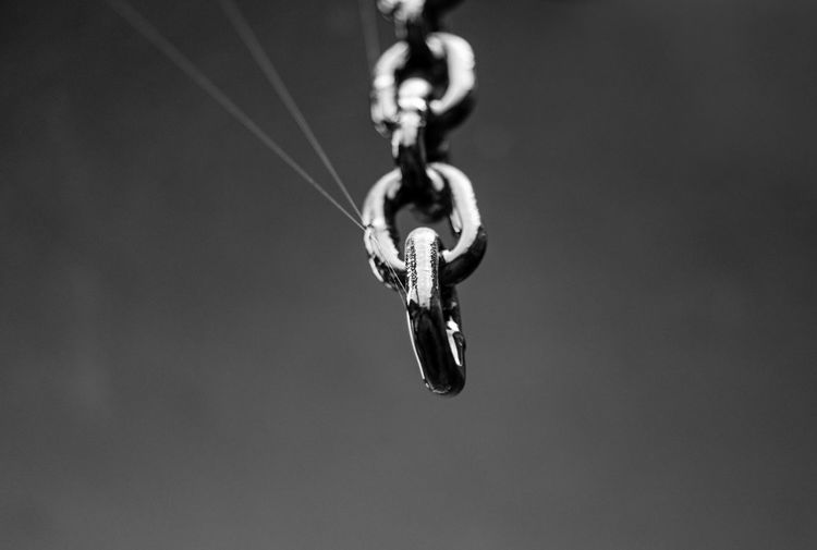 Low angle view of chain hanging on rope against sky