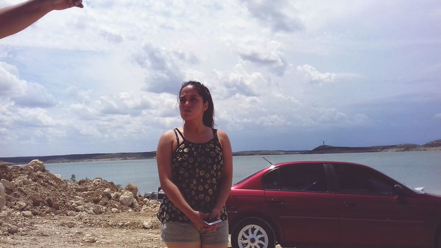 Woman standing at beach by car against sky