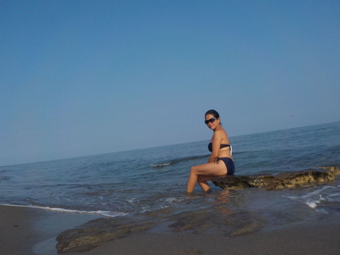 Young woman on beach against clear sky