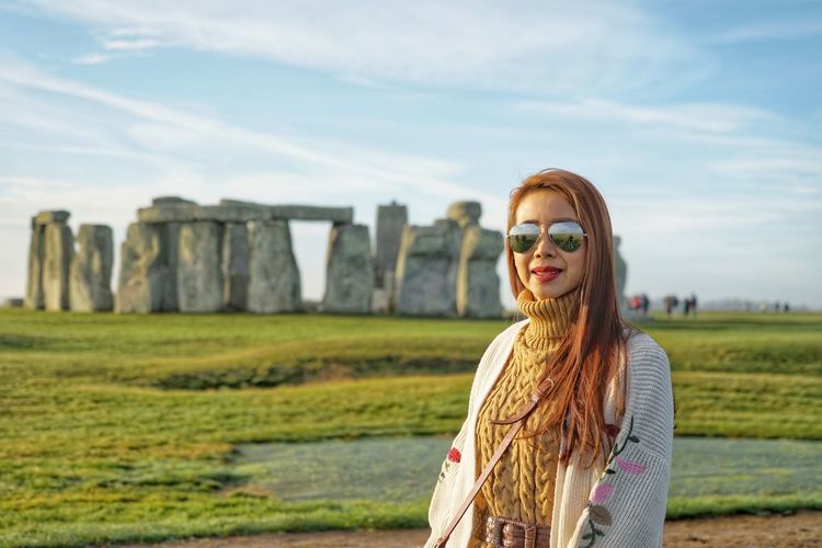 Portrait of woman standing at stonehenge against sky