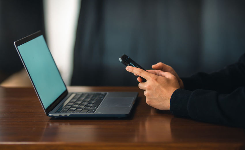 Midsection of woman using mobile phone on table