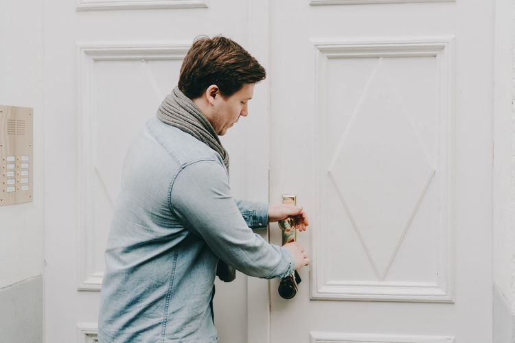 Mid adult woman standing against door at home