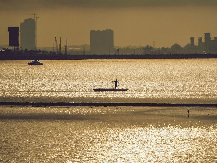 Silhouette man fishing during sunset