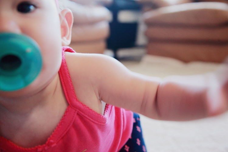 Close-up of baby girl with pacifier at home
