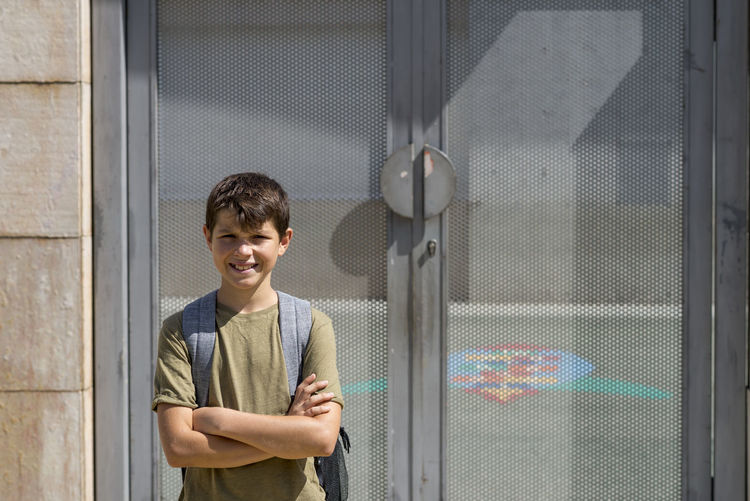 Portrait of smiling boy standing against closed door