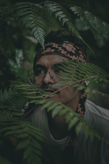 Close-up of young man standing amidst plants outdoors