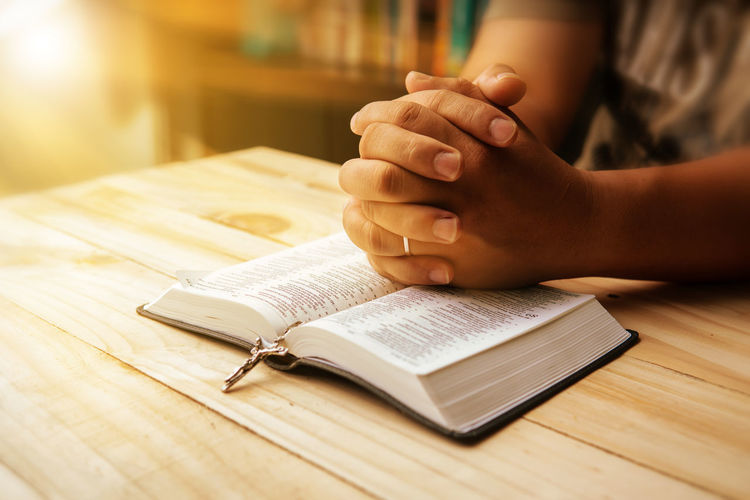 Midsection of woman reading bible at table