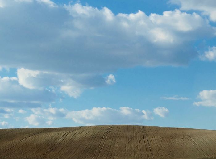 Idyllic shot of plowed field against blue sky