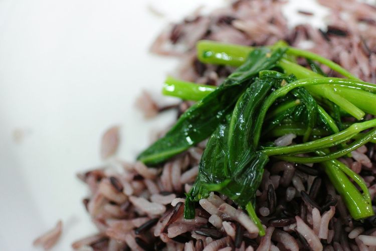 Close-up of brown rice with leaf vegetables on plate