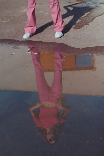 low section of woman standing at puddle
