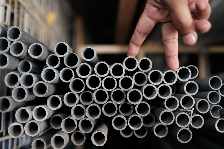 Close-up of hand choosing plastic pipes