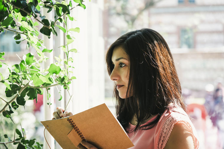 Beautiful agronomical engineer taking notes in the greenhouse