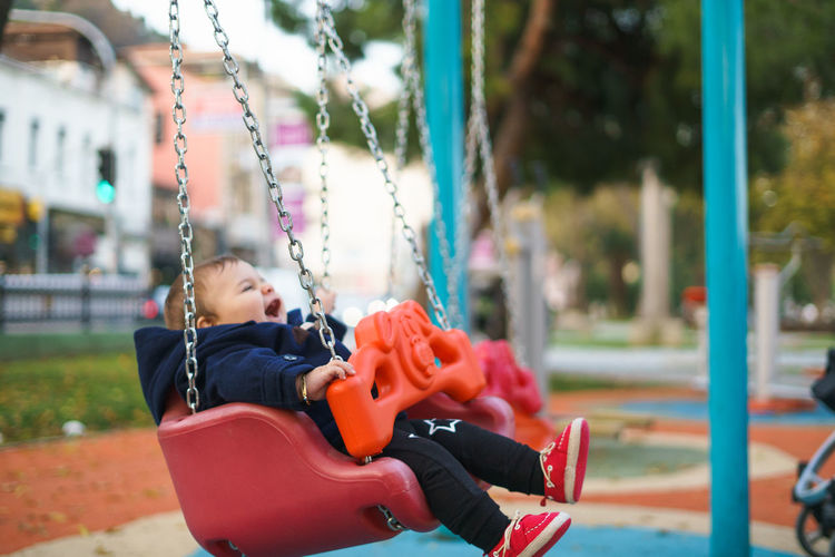 Baby boy sitting on swing at park
