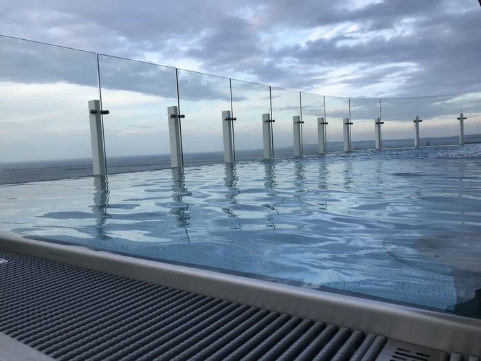 Wooden posts in swimming pool by sea against sky