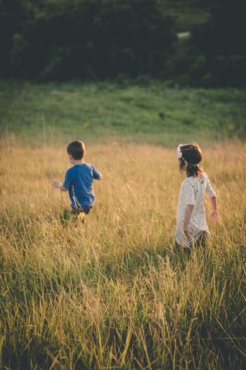 Rear view of siblings playing on field