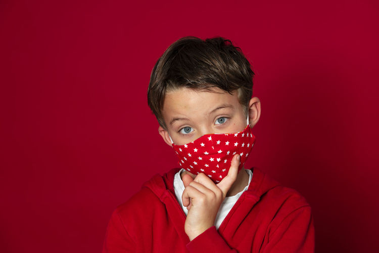Close-up portrait of boy against red background