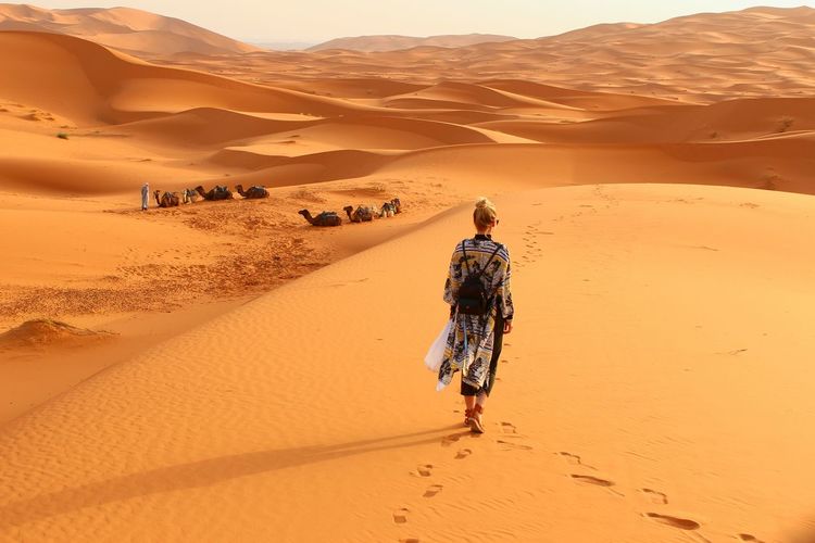 Rear view of woman walking in desert