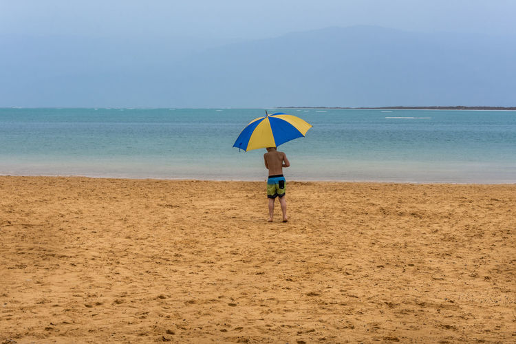 Boy holding sunshade on beach