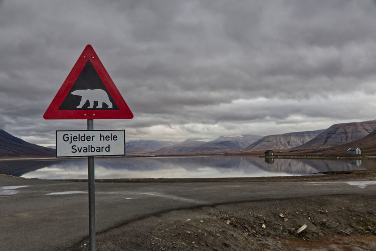 Polar bear warning sign against cloudy sky and arctic landscape in longyearbyen, spitzbergen