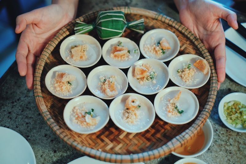 Cropped hands holding banh beo in wicker plate