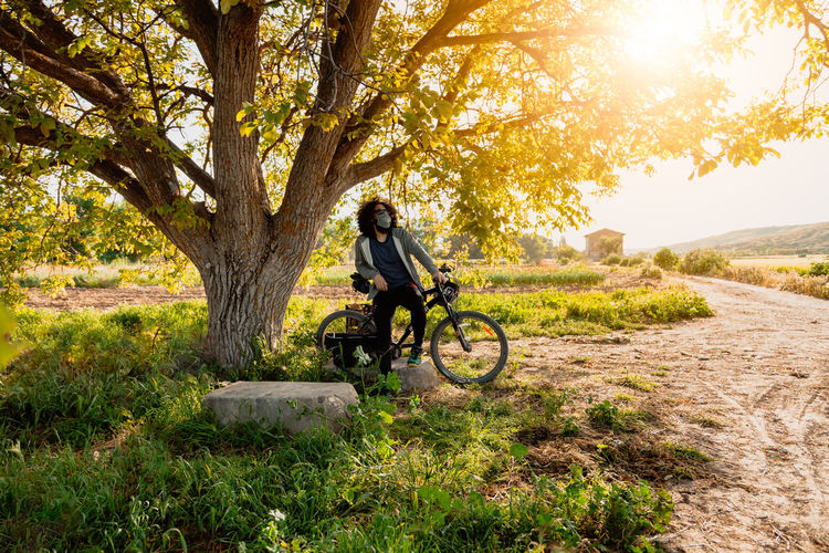 Man wearing mask sitting on bicycle in park