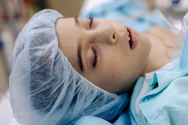 Close up of child with closed eyes in hospital cap and gown