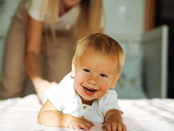 Young beautiful mother with long blond hair having fun with pretty baby boy at home
