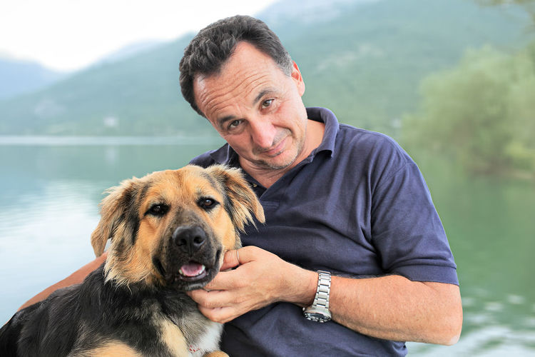 Portrait of man with dog against lake