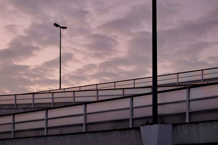 Low angle view of street light on bridge against cloudy sky